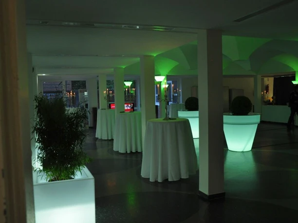 Beleuchteter Empfangsraum im Theater Meppen mit hohen Stehtischen und grüner Lichtgestaltung.