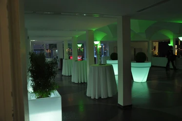 Theater im Windthorstgymnasium Meppen Beleuchteter Empfangsraum im Theater Meppen mit hohen Stehtischen und grüner Lichtgestaltung.