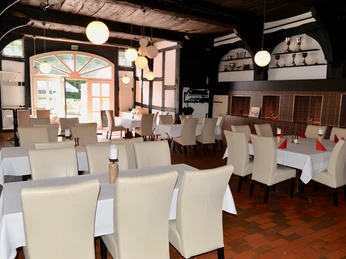 Ein Restaurant mit weißen Stühlen und gedeckten Tischen in einem traditionellen Fachwerkhaus.