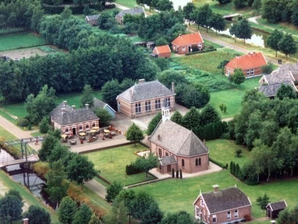 Veenpark - die Welt des Moores Luftaufnahme des Veenparks mit historischen Backsteinhäusern, Kirche und grünen Wasserkanälen.