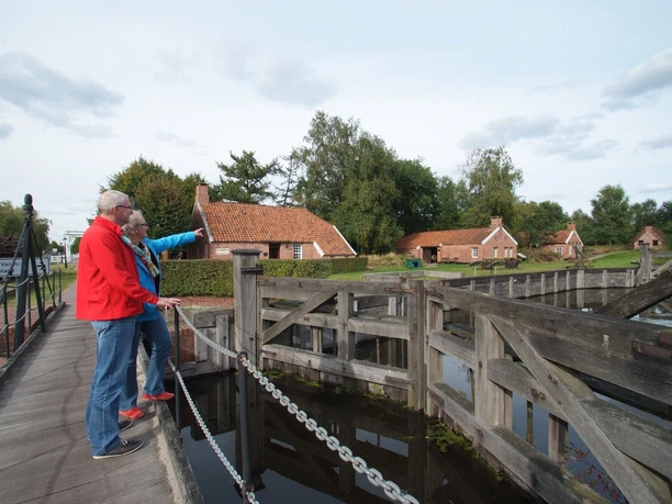 Von-Velen-Anlage Zwei Personen betrachten alte Schleusenanlagen vor historischen Backsteinhäusern im Freilichtmuseum.
