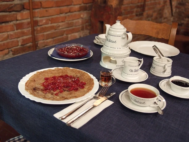 Von-Velen-Anlage Traditioneller gedeckter Tisch mit Tee, Likör, Buchweizenpfannkuchen und roter Grütze im Museumscafé.