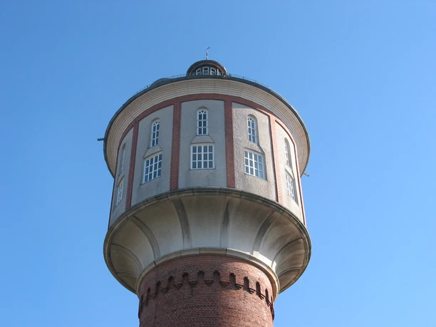 Lingen_Wasserturm.JPG Historischer Wasserturm in Lingen mit rotem Ziegelbau und runder Kuppel unter blauem Himmel.