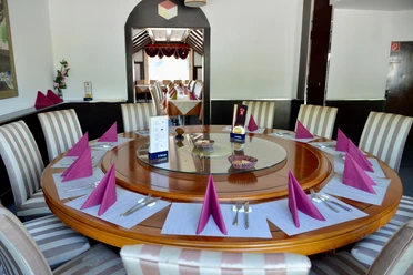 für gesellige Runden Ein großer runder Holztisch ist elegant gedeckt mit violetten Servietten und Besteck.