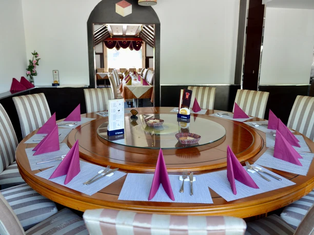 für gesellige Runden Ein großer runder Holztisch ist elegant gedeckt mit violetten Servietten und Besteck.