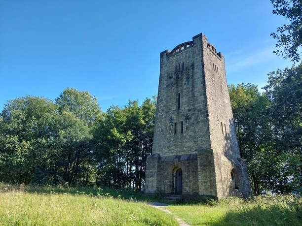 Bad Salzufler Bismarckturm aus Stein am Waldrand unter blauem Himmel