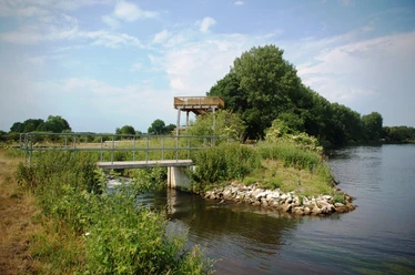 Aussichtsturm gelber Fluss Holzaussichtsturm am Ufer des Gelben Flusses mit Brücke, umgeben von Wasser, Bäumen und Wiesen.