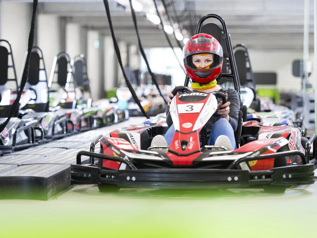 E-Kartbahn Nettedrom Fahrer in rotem Helm lenkt ein go-kartähnliches E-Fahrzeug auf der E-Kartbahn Nettedrom.