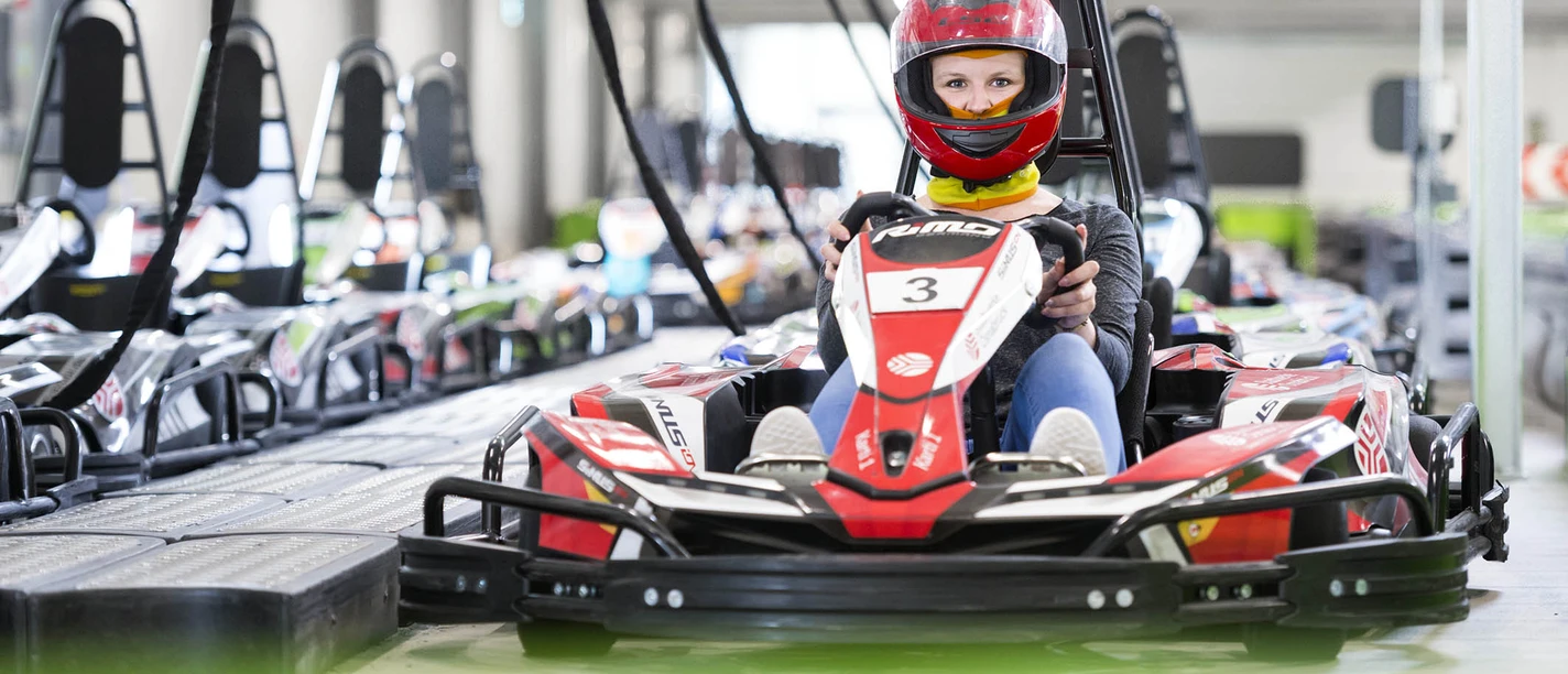 E-Kartbahn Nettedrom Fahrer in rotem Helm lenkt ein go-kartähnliches E-Fahrzeug auf der E-Kartbahn Nettedrom.