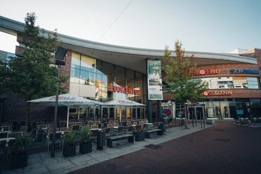 Lookentor Lingen Moderne Einkaufspassage mit Glasfassade, Außenbestuhlung und Geschäften in der Lingener Innenstadt.