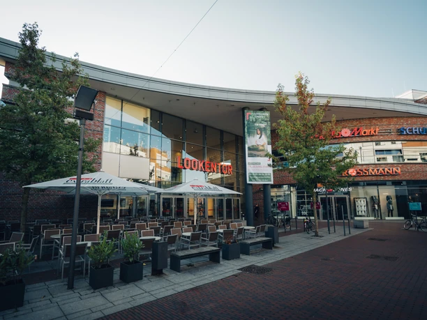 Lookentor Lingen Moderne Einkaufspassage mit Glasfassade, Außenbestuhlung und Geschäften in der Lingener Innenstadt.