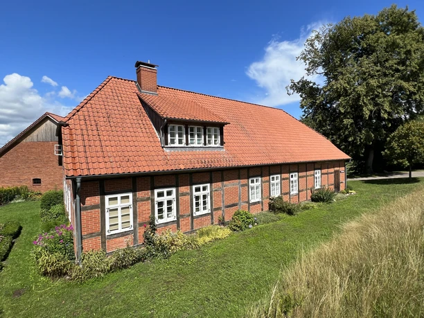 Müllerhaus Altes Müllerhaus mit rotem Ziegeldach, Fachwerkdetails und umgeben von grüner Natur.