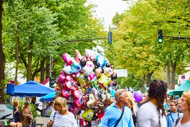 Lindenthaler Sommerfest Lebendiges Sommerfest auf der Dürener Straße mit bunten Ballons vor grünen Bäumen und fröhlichen Besucher*innen.