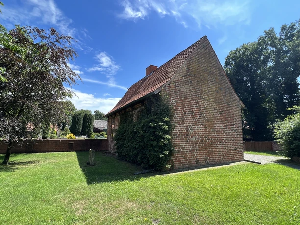 Kapitelhaus Wittlohe Historisches Backsteingebäude mit Satteldach, umgeben von gepflegtem Rasen und Bäumen im Sommer.