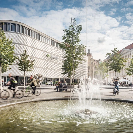 Summer hustle and bustle on the Richard Wagner Grove in Leipzig, with the Höfe am Brühl shopping center in the background.