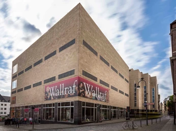 Wallraf-Richartz-Museum & Fondation Corboud Das Bild zeigt das beeindruckende Wallraf-Richartz-Museum in Köln. Der massive, moderne Bau dominiert die Straßenecke und zieht mit seiner schlichten Fassade und dem großen Banner "Wallraf" Besucher an.The picture shows the impressive Wallraf-Richartz Museum in Cologne. The massive, modern building dominates the street corner and attracts visitors with its simple façade and the large "Wallraf" banner.
