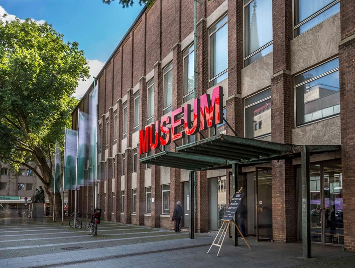 Museum für Angewandte Kunst Köln Das Bild zeigt die Fassade des Museums für Angewandte Kunst Köln mit auffälliger roter Neonschrift.The picture shows the façade of the Museum of Applied Arts Cologne with striking red neon lettering.
