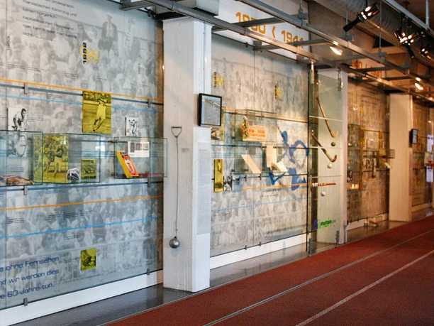 Deutsches Sport & Olympia Museum Innenansicht des Sportmuseums mit Ausstellungstafeln und Laufbahn, historische Aufnahmen im Hintergrund.