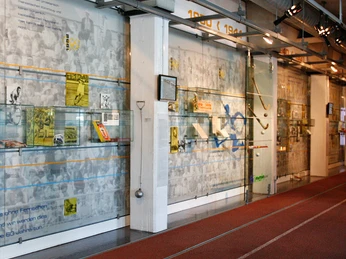 German Sport & Olympia Museum Innenansicht des Sportmuseums mit Ausstellungstafeln und Laufbahn, historische Aufnahmen im Hintergrund.Interior view of the sports museum with exhibition boards and running track, historical photos in the background.