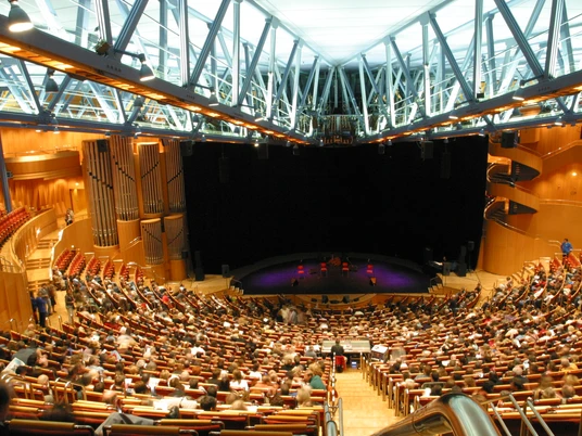 Kölner Philharmonie Innenansicht der Kölner Philharmonie mit voll besetztem Konzertsaal, modernen Holzwänden und einer beeindruckenden Orgel im Hintergrund.Interior view of the Cologne Philharmonic Hall with a full concert hall, modern wooden walls and an impressive organ in the background.