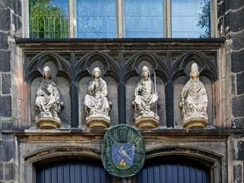 Sankt Severin Vier mittelalterliche Figuren blicken von einem gotischen Portal auf, darunter das Wappen von Köln.Four medieval figures look up from a Gothic portal, including the coat of arms of Cologne.
