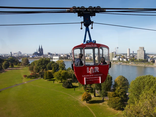 Rheinpark Die Kölner Seilbahn schwebt über den Rheinpark mit Blick auf den majestätischen Kölner Dom.