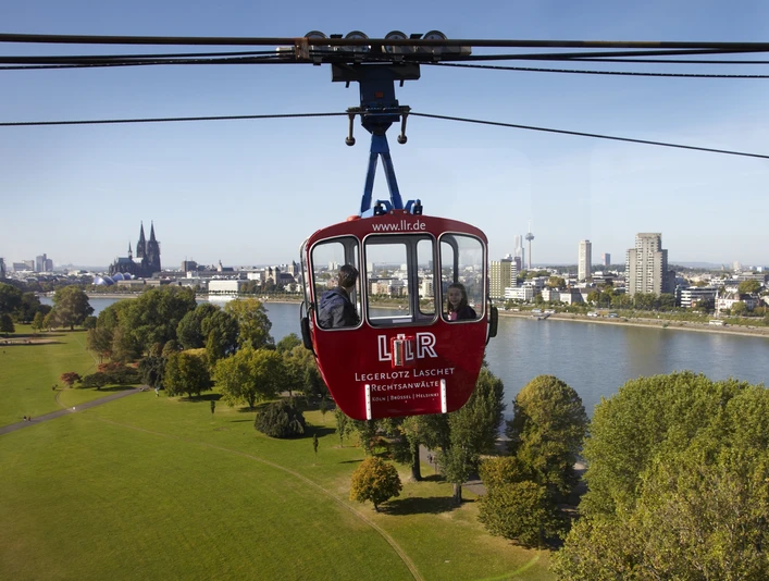 Kölner Seilbahn Die Kölner Seilbahn schwebt majestätisch über den Rhein, mit dem Kölner Dom und der Skyline der Stadt im Hintergrund.The Cologne cable car floats majestically over the Rhine, with Cologne Cathedral and the city skyline in the background.
