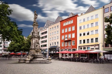 Jan von Werth Monument on the Alter Markt A lively square in Cologne's old town: colorful facades, cafés with red parasols, central fountain.