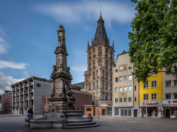 Jan von Werth Monument The picture shows the Old Market in Cologne with its imposing town hall tower, flanked by historic house facades and an impressive fountain in the foreground.
