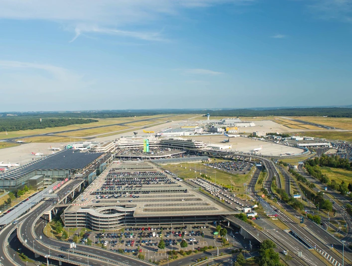 Köln Bonn Airport Luftaufnahme des Flughafens Köln/Bonn mit Terminalgebäuden, Parkplätzen und Start-/Landebahnen bei blauem Himmel.Aerial view of Cologne/Bonn Airport with terminal buildings, parking lots and runways under a blue sky.