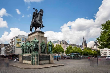 Reiterstandbild König Friedrich Wilhelm III. Denkmal des preußischen Königs auf einem Pferd, umringt von Statuen in belebter Altstadt mit Domblick.