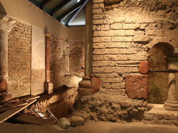 MiQua Im Bild sind die jahrhundertealten Mauern einer Mikwe in warmen, erdigen Farben zu sehen. Altertümliche Steinstrukturen und eine gedämpfte Beleuchtung schaffen eine meditative, ruhige Atmosphäre.