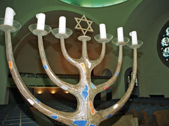 Synagoge Der Bildausschnitt zeigt eine kunstvoll gestaltete Menora mit sechs Armen und einem Davidstern im Hintergrund in der Synagoge an der Roonstraße in Köln.The image detail shows an artistically designed menorah with six arms and a Star of David in the background in the synagogue on Roonstraße in Cologne.