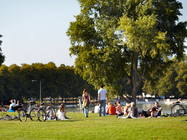 Aachener Weiher Menschen entspannen im Sommer auf einer grünen Wiese am Aachener Weiher, Fahrräder liegen bereit.
