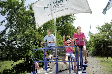 Draisinenbahnhof Familie fährt Draisine mit Hund im Grünen