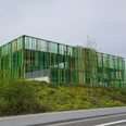 Modernes Gebäude mit einer auffallenden Fassade aus grünen und orangen vertikalen Streifen, gelegen in einer urbanen Umgebung.
