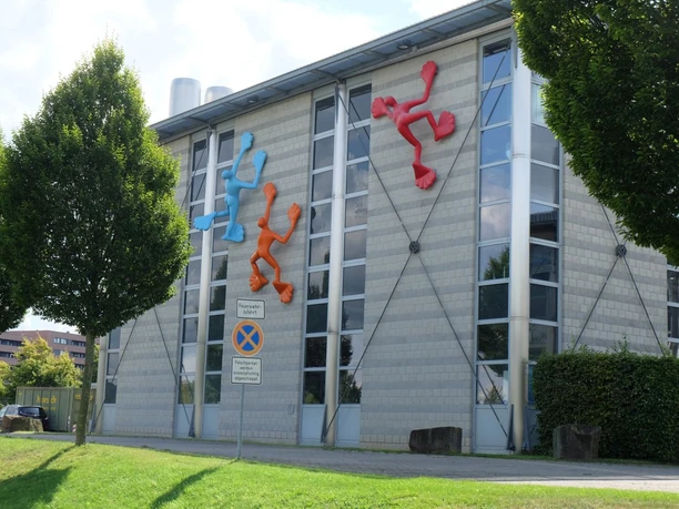 Campus Melaten Moderne Gebäude mit bunter, künstlerischer Wandgestaltung, umgeben von grüner Natur.