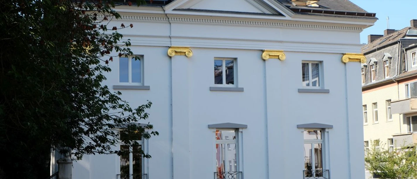 Burtscheid Historisches, weiß verputztes Gebäude mit goldenen Verzierungen.
