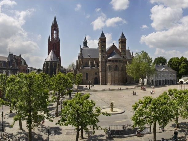 Maastricht Marktplatz Panoramaaufnahme von einem großen Markplatz, der umgeben von Häusern, Bäumen und einer großen Kirche ist.