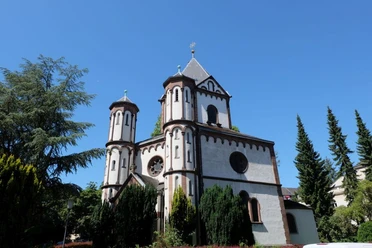 Marienkapelle Burtscheid Romanische Marienkapelle mit weißem Mauerwerk und kunstvollen Türmen, von Grün umgeben.