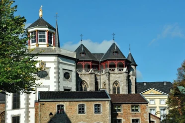 St. Kornelius Fassade von einer Kirche mit gotischen Elementen und einem achteckigen, rot und gold verzierten Turm.
