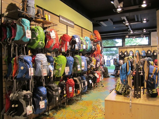 Intersport Drucks Wandregale, an denen viele Wanderrucksäcke in verschiedenen Farben hängen.