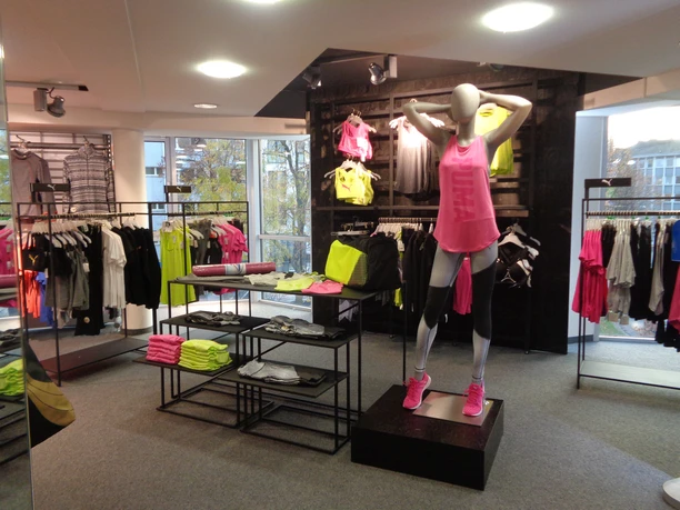 Intersport Drucks Schaufensterpuppe in leuchtend pinker Sportkleidung und Regale mit weiteren Sportartikeln.