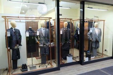 Schaufenster mit mehreren Mannequins, die Anzüge tragen.