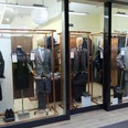 Schaufenster mit mehreren Mannequins, die Anzüge tragen.
