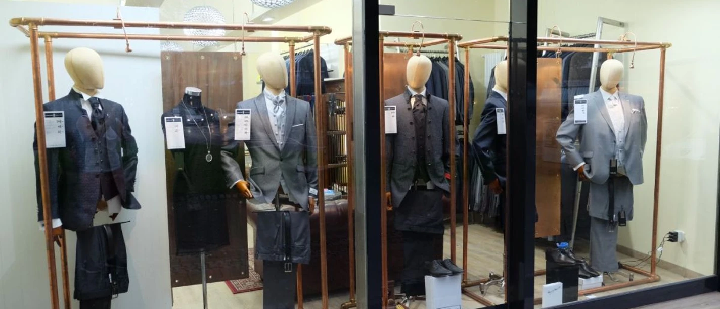 Wienand Schaufenster mit mehreren Mannequins, die Anzüge tragen.