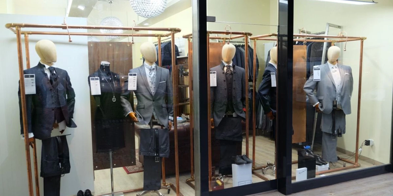 Wienand Schaufenster mit mehreren Mannequins, die Anzüge tragen.