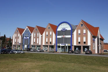 Bakstenen gevel met rode zadeldaken en een blauwe ingangsgevel van modehuis Wübben in Haselünne