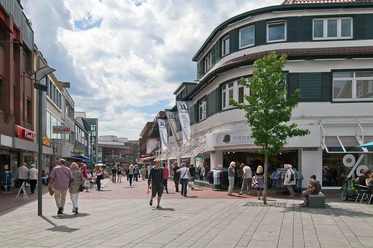 Innenstadt Lingen Belebte Fußgängerzone in Lingens Innenstadt mit Geschäften, Passanten und Straßencafés bei Sonne.