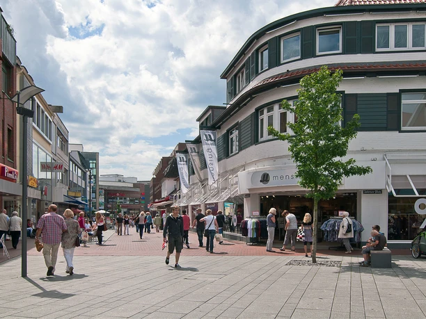 Innenstadt Lingen Belebte Fußgängerzone in Lingens Innenstadt mit Geschäften, Passanten und Straßencafés bei Sonne.